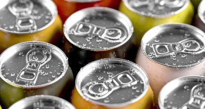 Close-up of cold, colorful drink cans with water droplets on their pull-tab lids