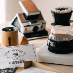 Pour-over dripper, kettle, mug, and hand grinder arranged as coffee gift ideas with wrapped kraft paper