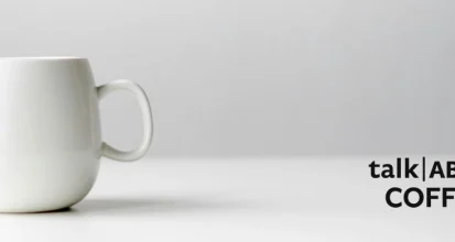 A cup of coffee on a desk with research papers illustrating coffee and Alzheimer disease research
