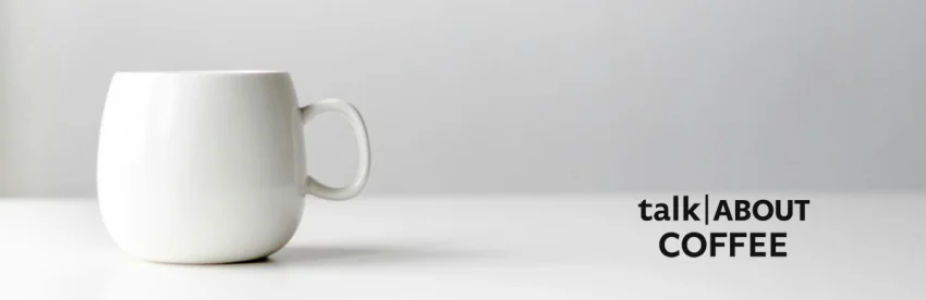 A cup of coffee on a desk with research papers illustrating coffee and Alzheimer disease research