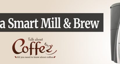 Melitta Smart Mill & Brew coffee maker in black and silver, with an LCD screen showing time, temperature and sunset data beside a glass carafe