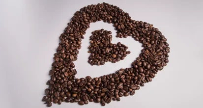 Bowls of single-origin coffee beans from different regions arranged on a wooden table with origin labels