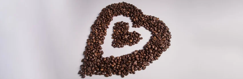 Bowls of single-origin coffee beans from different regions arranged on a wooden table with origin labels