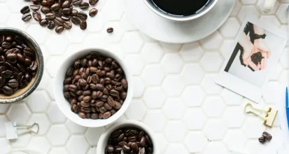 Bowls of different single-origin coffee beans beside handwritten tasting notes and a cup of black coffee