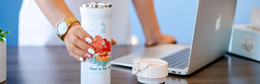 Insulated travel mug on a desk as a coffee gift idea for coworkers and clients