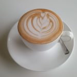 Overhead view of a latte with rosetta-pattern latte art on a white saucer