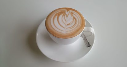 Overhead view of a latte with rosetta-pattern latte art on a white saucer