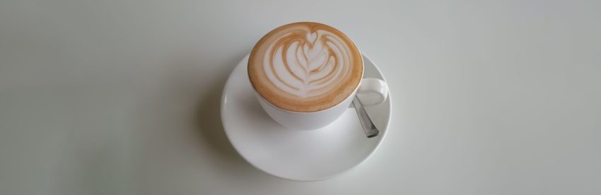 Overhead view of a latte with rosetta-pattern latte art on a white saucer
