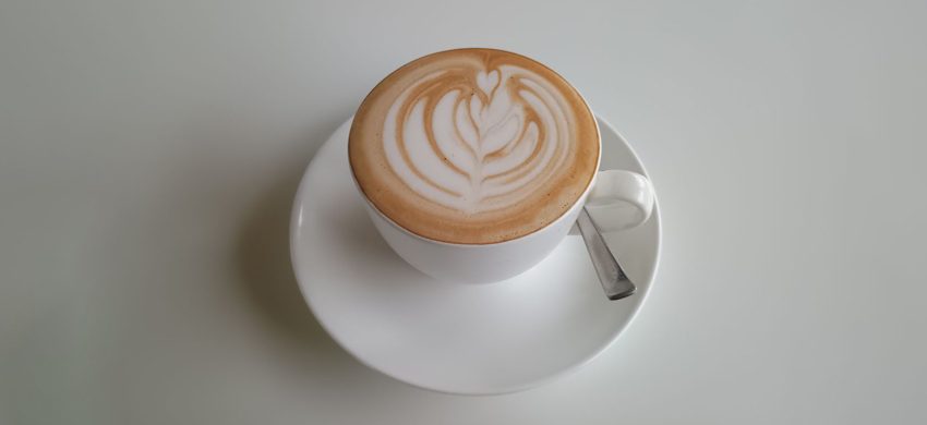 Overhead view of a latte with rosetta-pattern latte art on a white saucer